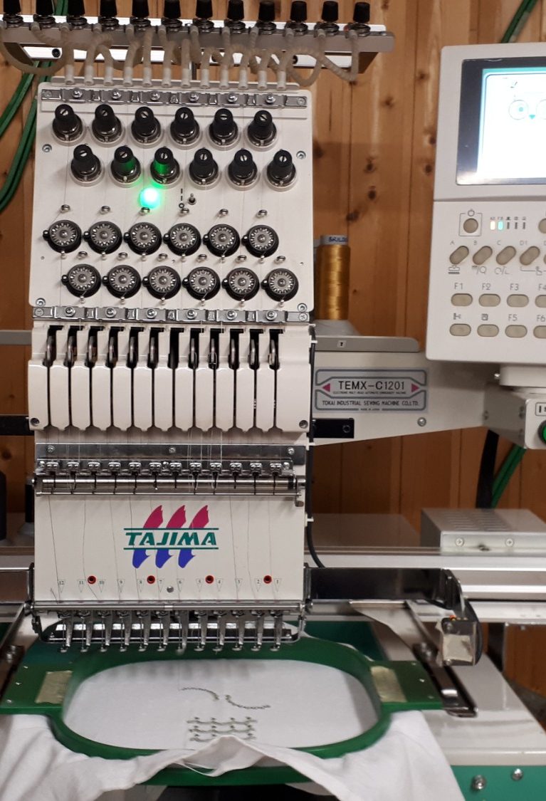 Eulenstick Industrielle Stickmaschine mit buntem gestickten Logo auf einem Stoff.